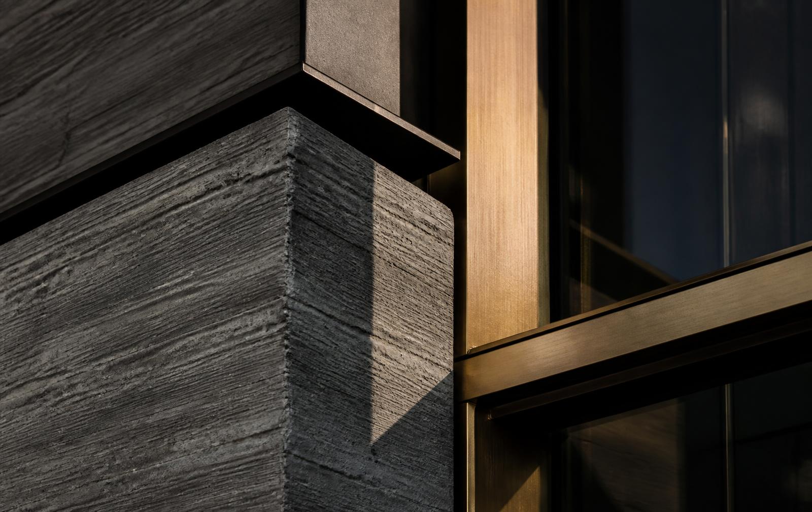 Board-formed concrete meeting brushed bronze on the VANTAGE facade